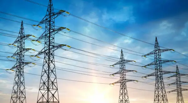 Wieże energetyczne na tle zachodzącego słońca, symbolizujące maksymalne napięcie w sieci.