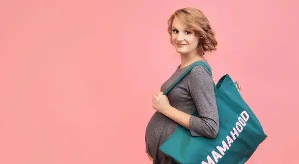 Przyszła mama z torbą "Mamahood" na ramię, gotowa na poród. Idealna torba do szpitala na operację.