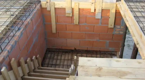 Budowa schodów drewnianych: szalunek z desek i cegieł, zbrojenie pod beton.
