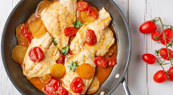 Orata in padella con pomodorini e patate, un piatto succulento e colorato, pronto per essere gustato.