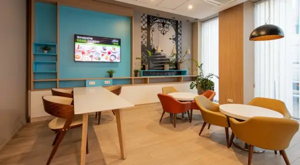 Wygodna strefa wypoczynkowa w hotelu B&B Łódź z kolorowymi fotelami i stołami, idealna na poranną kawę.