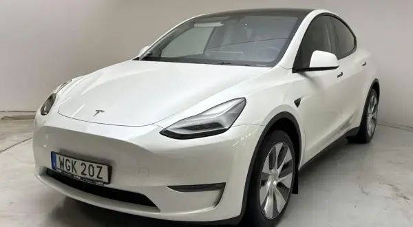Vit Tesla Model Y, en begagnad elbil med mörk taklucka och stilrena fälgar. Perfekt för den miljömedvetna föraren.