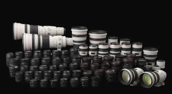 Vasta collezione di obiettivi per fotocamere, con diversi modelli e marche di macchine fotografiche, disposti su sfondo nero.