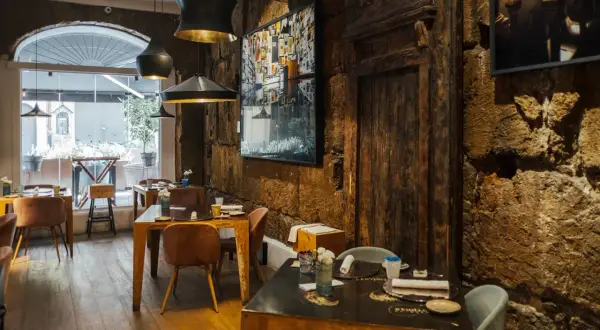 Interno di un ristorante con tavoli apparecchiati e pareti in pietra grezza. Un'atmosfera che fa pensare ai migliori ristoranti di Palermo.