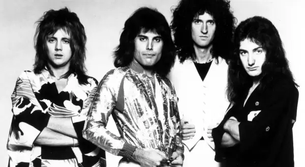 Czterech członków zespołu Queen, Freddie Mercury, Brian May, Roger Taylor i John Deacon, pozuje do zdjęcia. To oni tworzą zespół Queen, który nagrał największe hity.