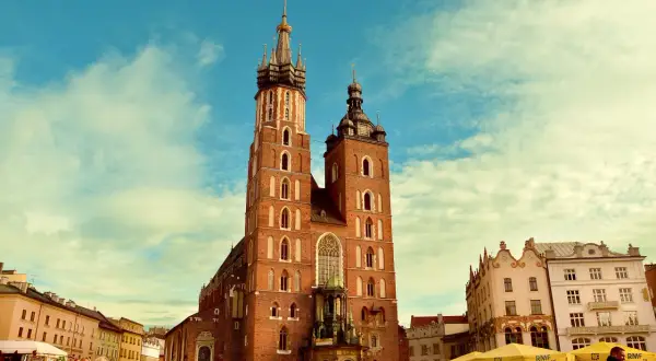 Bazylika Mariacka w Krakowie, jedno z najpiękniejszych miejsc historycznych w Polsce, na tle błękitnego nieba z chmurami.