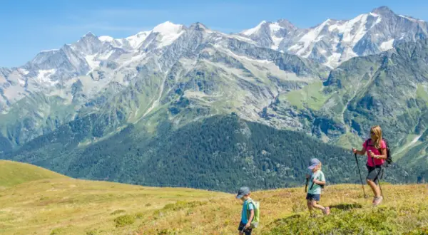 Famille en randonnée, profitant de leurs vacances montagne été. Paysage alpin spectaculaire sous un ciel bleu.