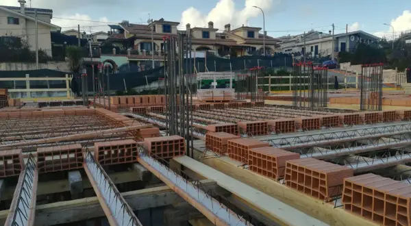 Cantiere edile con mattoni e armature in vista. Si sta preparando il miglior isolante termico per soffitto, con blocchi di laterizio pronti per la posa.