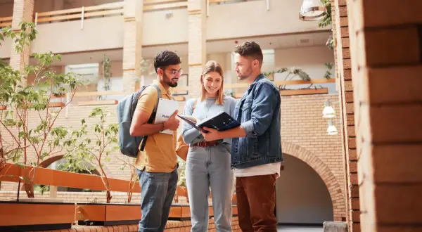 Drei Studierende planen ihren Auslandssemester Master in einem modernen Gebäude.