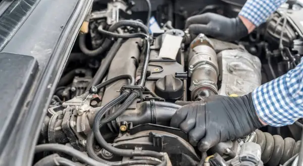 Mechanik w rękawiczkach naprawia silnik Renault, być może z powodu błędu dtc p0141.