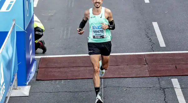 Nicolas franchit la ligne d'arrivée, son kit marathon impeccable. Il a l'air épuisé mais heureux.