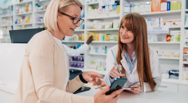 Klientka pokazuje farmaceutce telefon, szukając odpowiedzi na pytania zamknięte przykłady.
