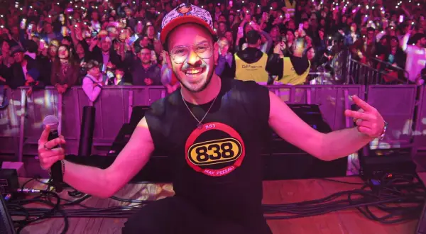 Max Pezzali sul palco, con la folla illuminata dai cellulari, indossa una maglietta con il logo 883.