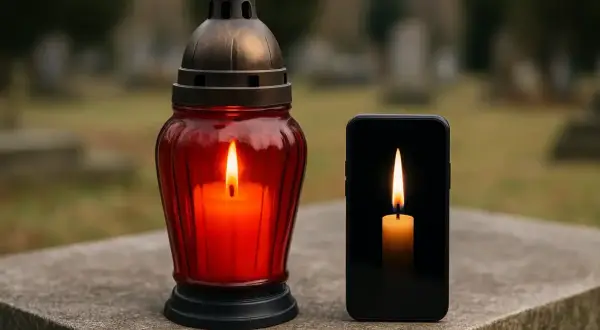 Znicz i płonąca świeca na ekranie telefonu na tle cmentarza.