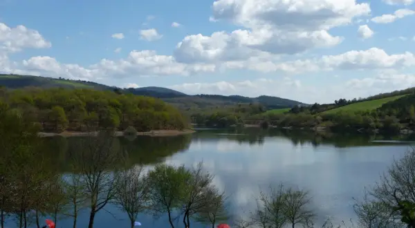El embalse de Vilasouto, con sus aguas serenas reflejando el cielo azul y las verdes colinas, invita a disfrutar de un día tranquilo.