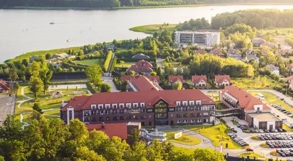 Widok z lotu ptaka na kompleks hotelowy Radisson z czerwonymi dachami, otoczony zielenią i jeziorem.