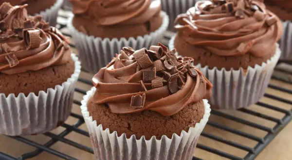 Schoko cupcakes mit cremiger Schokoladenfüllung und Schokostreuseln, auf einem Gitterrost.