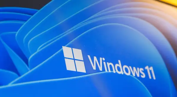 Nawet stary komputer może działać z Windows 11, pokazany na niebieskim tle z logo.