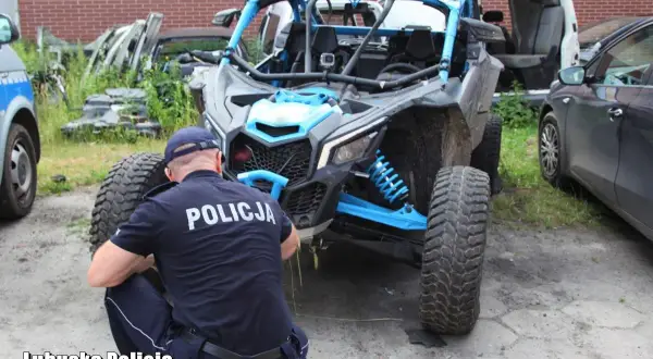 Policjant w mundurze bada quada z niebieskimi elementami.