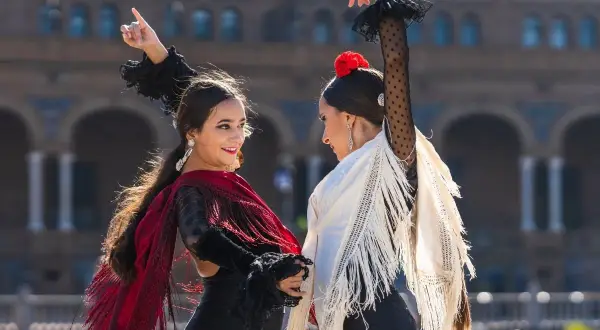 Dos mujeres bailan flamenco con mantones. ¡Perfecto para clases de flamenco para adultos!