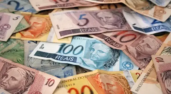 Stosy banknotów, w tym 100, 10 i 5 reali, stanowią walutę Brazylii.