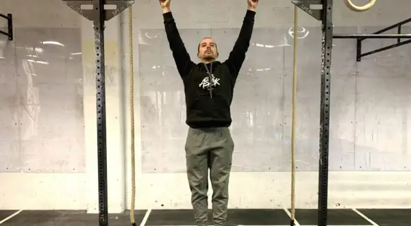 Un homme en tenue de sport s'accroche à une barre de traction, prêt à commencer son programme traction.