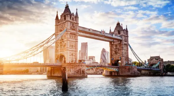 Tower Bridge w Londynie o zachodzie słońca, z nowoczesnymi wieżowcami w tle.