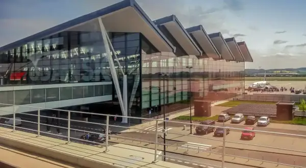 Nowoczesny budynek lotniska Gdynia z przeszkloną fasadą i samolotem na płycie lotniska.