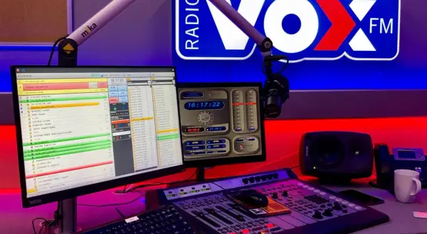 Studio radiowe Vox FM z komputerami, mikserem i mikrofonem.
