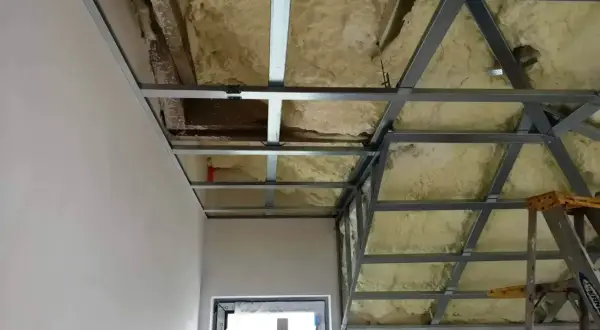 Konstrukcja podwieszanego sufitu z metalowymi profilami i izolacją piankową, gotowa do dalszych prac wykończeniowych.