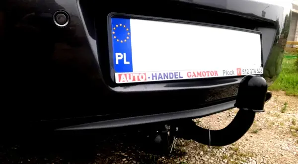 Widok z tyłu samochodu Opel Insignia z zamontowanym modułem haka. Widoczna tablica rejestracyjna i czujnik parkowania.