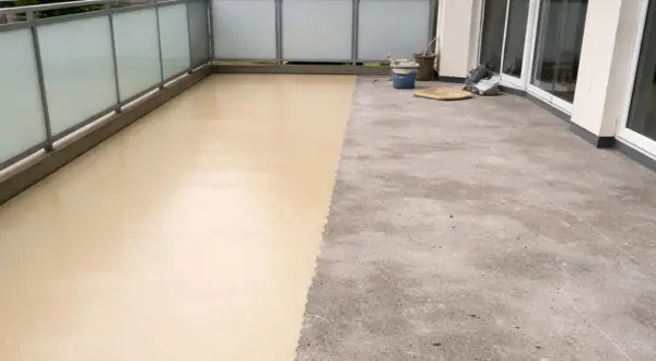 Balcone con pavimenti in resina per esterni: metà grezzo, metà beige applicato. Valutare pro e contro per una scelta informata.