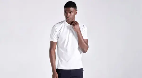 Ein Mann in einem weißen Poloshirt, das klassische Merkmale wie den Kragen und die Knopfleiste zeigt.
