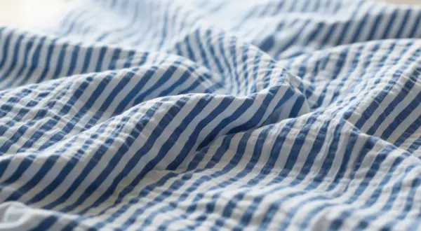 Blau-weißer Seersucker-Stoff mit charakteristischen Falten. Dieses Gewebe ist leicht und luftig, perfekt für Sommerkleidung.