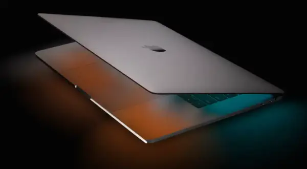 Elegancki MacBook Pro 16 z podświetlaną klawiaturą, otoczony ciepłym i chłodnym światłem, gotowy do pracy.