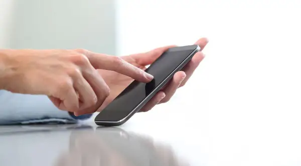 Dłonie trzymające smartfon, pokazujące jak doładować telefon w Play na kartę.