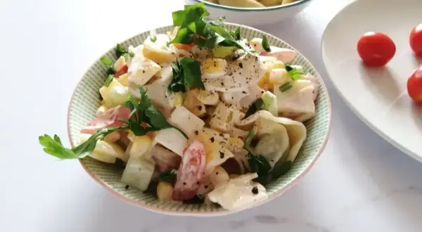 Pyszna sałatka z tortellini, jajka, kukurydzy i pomidorów, polana kremowym sosem. Idealna na szybki obiad lub kolację.