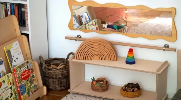 Holzspielzeug, Bücher und Körbe für ein gemütliches Kinderzimmer einrichten. Ein Holzregal mit Regenbogen und Stapelturm.