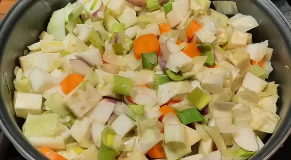 Poêlée de légumes coupés en dés, prêts pour un savoureux bouillon de légume. Carottes, poireaux et navets se mélangent.