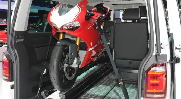Una moto deportiva roja lista para transportar en furgoneta, asegurada con correas sobre un riel.