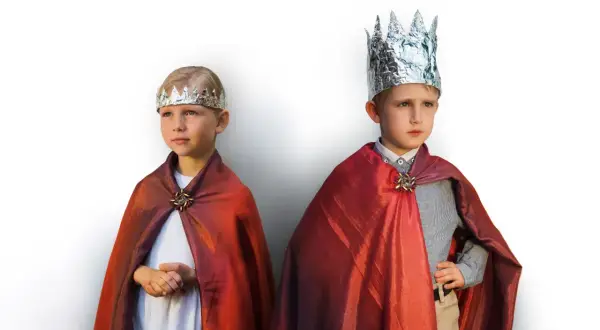 Dwóch chłopców w strojach hiszpańskich królów, z błyszczącymi koronami i czerwonymi pelerynami.
