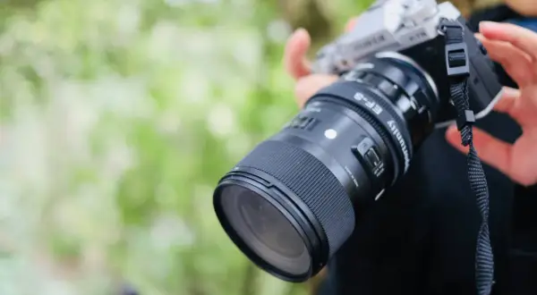Srebrny aparat fotograficzny dla początkujących z obiektywem Sigma EF-S. Idealny do nauki fotografii.