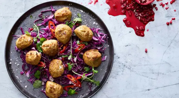Falafel i airfryer serveras på en bädd av rödkål med strimlad paprika och granatäpple.