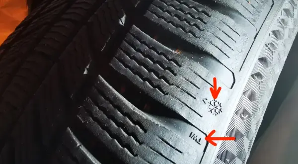 Widoczne są oznaczenia na bieżniku opony, w tym symbol płatka śniegu i wskaźnik zużycia opony.