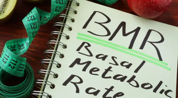 BMR co to? Notatnik z napisem "Basal Metabolic Rate", miarka krawiecka i owoce kiwi oraz jabłko.