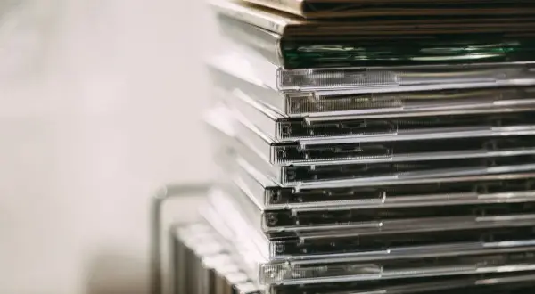 Stos przezroczystych pudełek z płytami CD, idealny do przechowywania nowości płytowych.