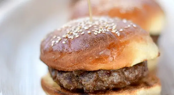 Mini burgery na puszystych bułkach do burgerów, posypane sezamem, gotowe do podania.