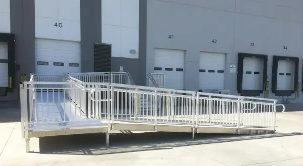 A modular wheelchair ramp system is installed outside a warehouse, providing accessibility to loading docks. This shows how to build a wheelchair ramp for easy access.