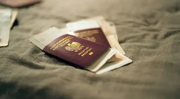 Kilka paszportów leży na szarym materiale. Zastanawiasz się, jak wyrobić paszport? To pierwszy krok do podróży!