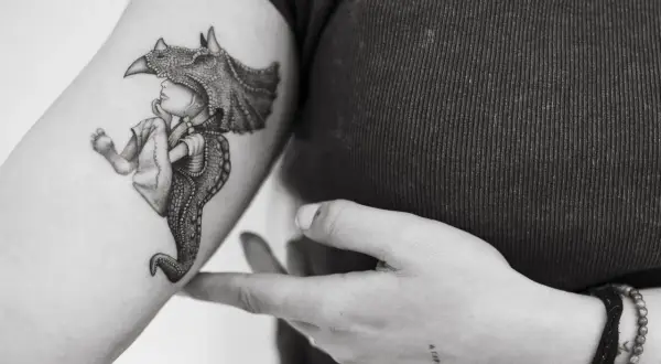 Un tatuaje de un niño con un casco de dinosaurio, con detalles intrincados, que evoca la magia de los tatuajes sevillanos.